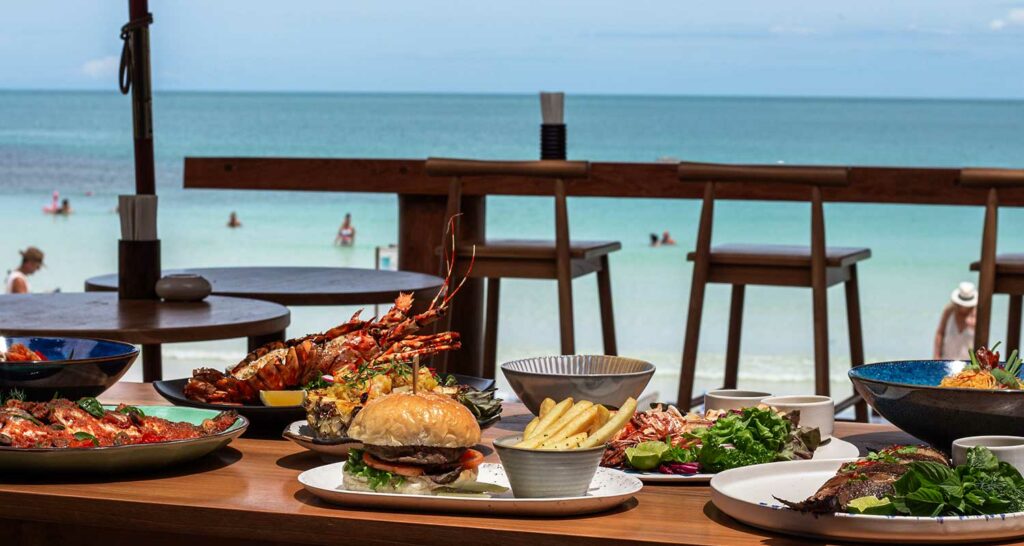 Table of food in restaurant with sea in the background